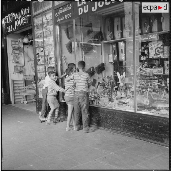 Un groupe de jeunes garçons est rassemblé devant la vitrine d'un magasin de jouets, dans la ville d'Alger.