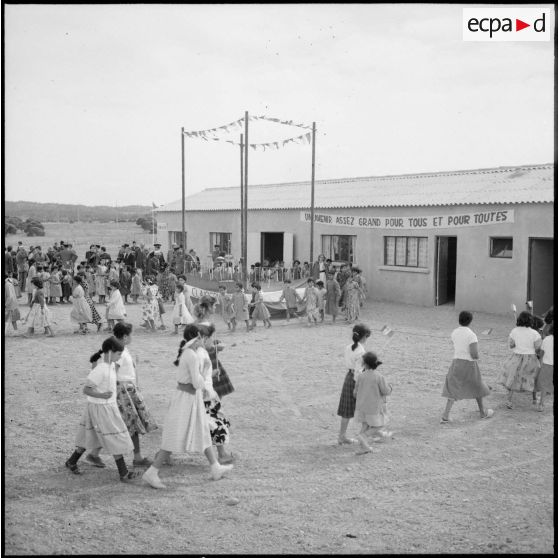 Des fillettes munies de drapeaux gagnent leur place pour l'inauguration du foyer des jeunes de Clairfontaine.