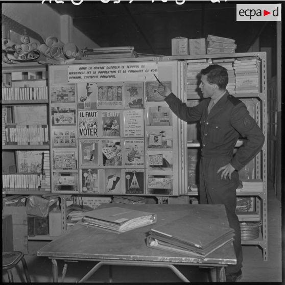 Dans un bureau de l'imprimerie du 5e bureau, un employé pointe une affiche de propagande.