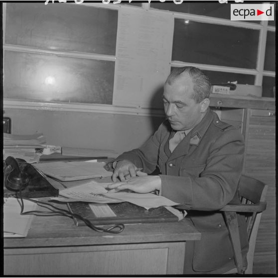 Assis à son bureau, un employé de l'imprimerie du 5e bureau travaille à la rédaction d'un texte de propagande.