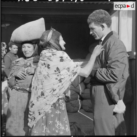 L'officier des affaires musulmanes Abada Youssef supervise la distribution des sacs d'orge aux femmes.