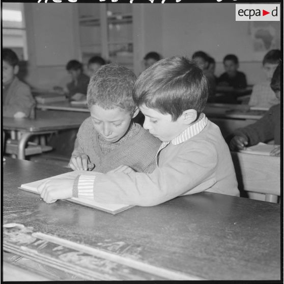 Portrait de deux élèves qui travaillent à leur bureau dans la salle de classe.