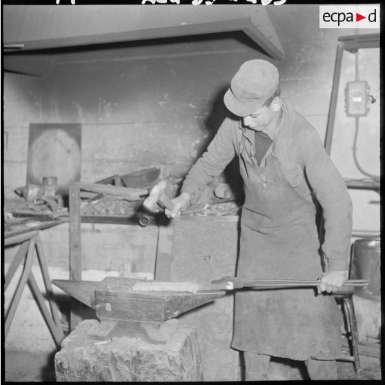 Centre de formation de la jeunesse algérienne : à l'intérieur de l'atelier de métallurgie, portrait d'un élève âgé de 17 ans, de Novi, en plein travail de forge.