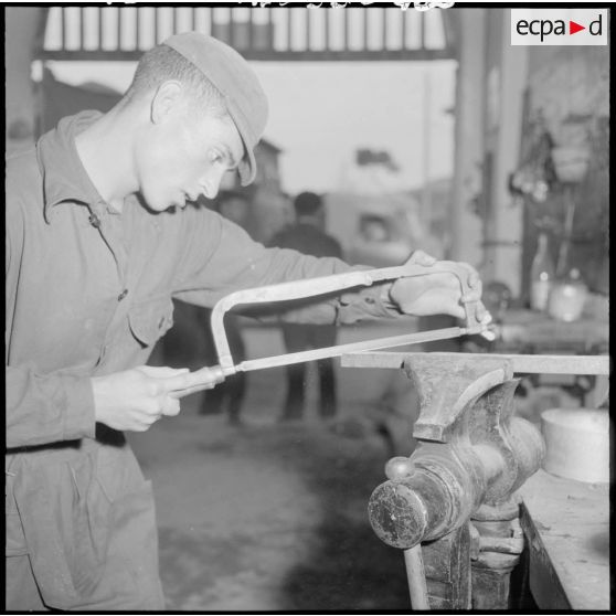 Centre de formation de la jeunesse algérienne : à l'intérieur de l'atelier de menuiserie, portrait d'un élève âgé de 16 ans, de Maison-Carrée, en plein travail.