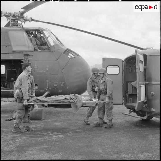 Alger. Transfert des blessés à l'héliport Cerdan. Sortie du blessé de l'hélicoptère Sikorsky H-34 pour le transférer dans une ambulance.