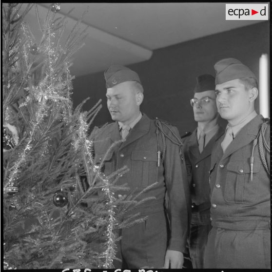 Des soldats décorent un arbre de noël.