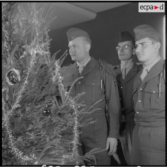 Des soldats décorent un arbre de noël.