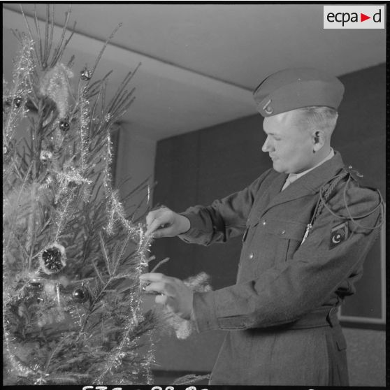 Un soldat décore un arbre de noël.