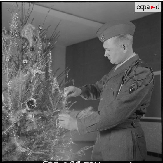 Un soldat décore un arbre de noël.