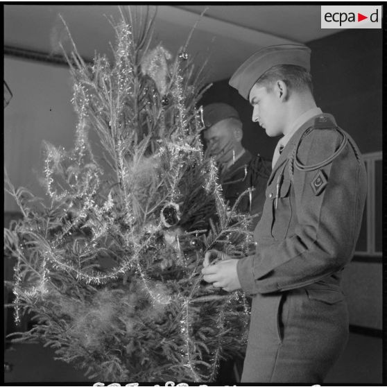 Des soldats décorent un arbre de noël.