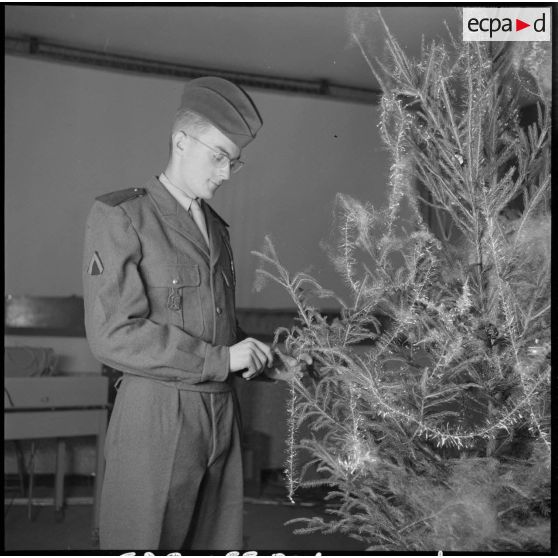Un soldat décore un arbre de noël.