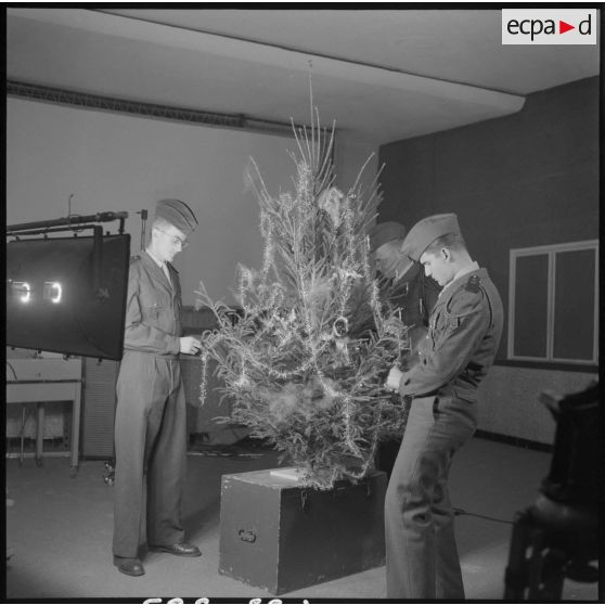 Des soldats décorent un arbre de noël.