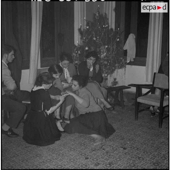 Veillée de Noël au foyer Panorama. Un jeune garçon accompagne à la guitare, ces quelques jeunes filles, dans les chants de noël.