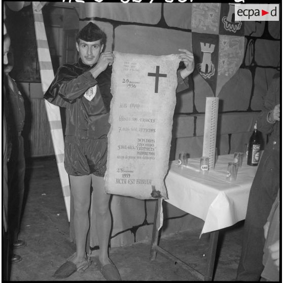 Arbre de Noël à l'imprimerie. Un soldat déguisé en chevalier montre le bilan réalisé depuis 1956, noté sur un parchemin.