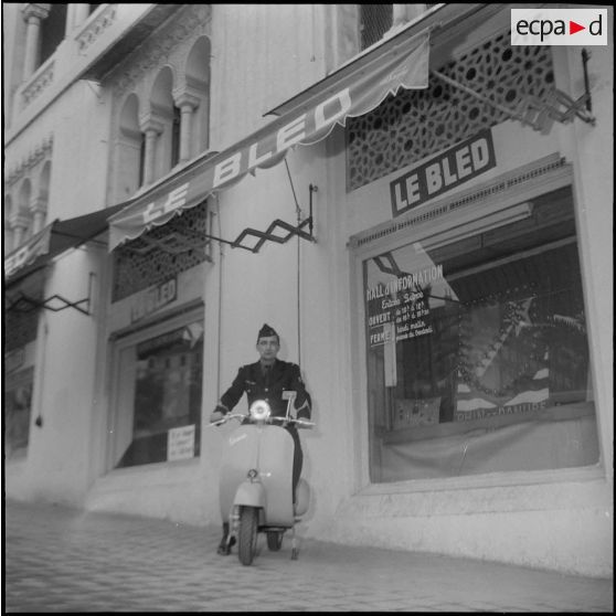 Un aviateur devant le siège du journal Le Bled à Alger avec son scooter. [Description en cours]