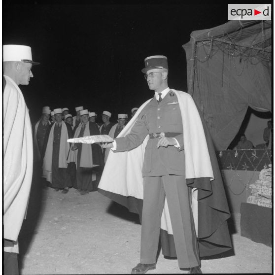 Distribution de cadeaux par le Capitaine Gilbert, commanadant (Cdt) la 1re compagnie saharienne portée de légion étrangère (CSPL).