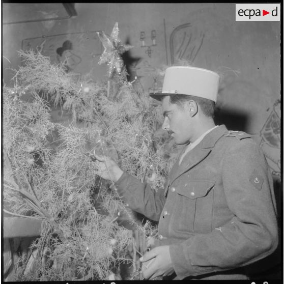 Noël au fond du désert. Un soldat  de la compagnie saharienne décore un arbre de Noël.