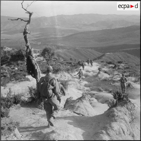 Les commandos Harkis sur les hauteurs assurent la protection des civils transportants leurs affaires vers le village regroupé.