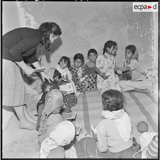 Colomb-Béchar. Une institutrice apprend la lecture à des petites filles.