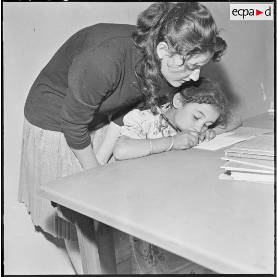 Colomb-Béchar. Une institutrice apprend l'écriture à une petite fille.