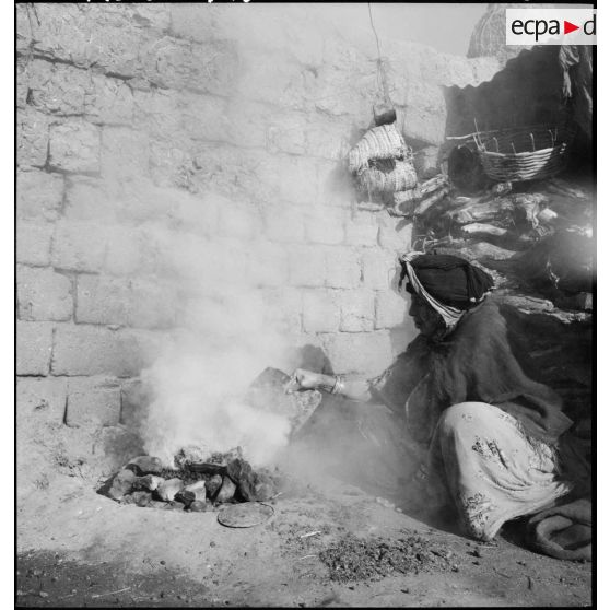 Timgad. Une femme prépare un feu.