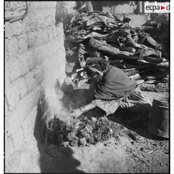 Timgad. Une femme prépare un feu.