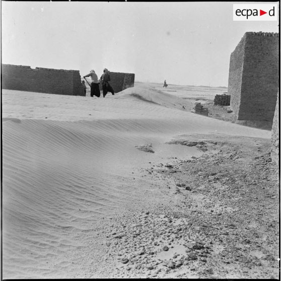 Ensablement de la ville d'In Salah. Des hommes retirent le sable.