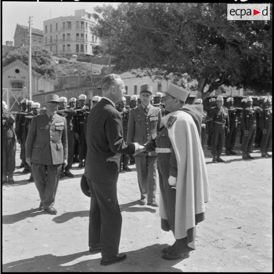 Prise d'armes à Mostaganem. Pierre Messmer salue une autorité militaire.
