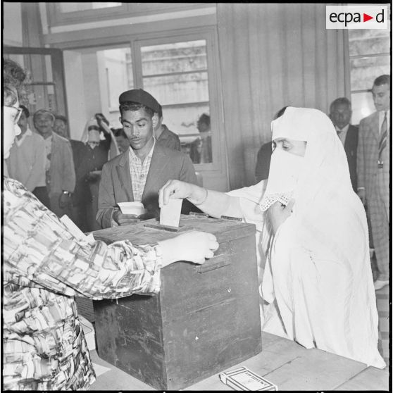 Casbah d'Alger. Elections cantonales du 29 mai 1960. Dans le calme les électeurs attendent et votent. Une femme glisse son bulletin de vote dans l'urne.