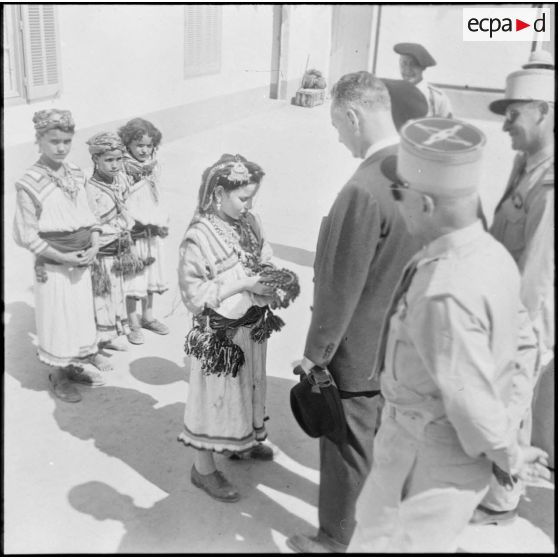 Grande Kabylie. Pierre Messmer reçoit des mains d'une petite fille kabyle une broche de fabrication locale.