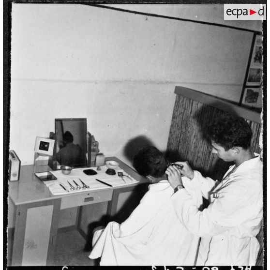 Beni-Messous. Camp Basset. Compagnie de circulation routière 210 (CCR 210). Le 2e classe de la 59/2C coupe les cheveux à l'un de ses camarades.