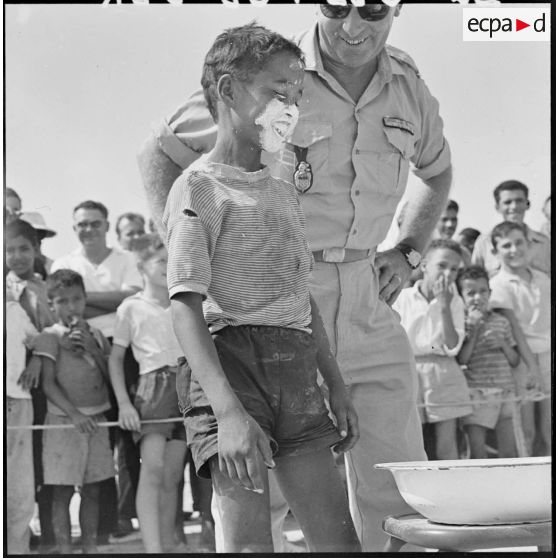 Colomb-Béchar. Festivités du 14 Juillet 1960 dans la zone ouest sud (ZOS). Les jeux dirigés par la gendarmerie attirent les enfants qui se pressent autour des stands improvisés.