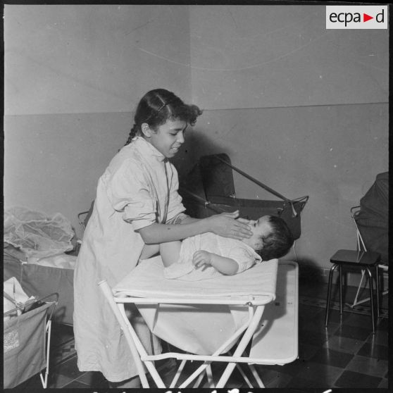 Alger. Le Berceau. La préposée aux bébés lange l'un d'eux.