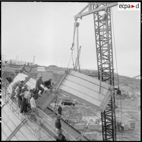 Construction du barrage du Mefrouch. Pose d'un élément préfabriqué sur une des voutes du barrage.