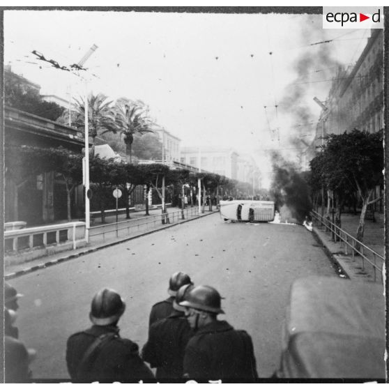 Alger. Manifestations du 10 décembre 1960. Une voiture Peugeot 403 commerciale renversée brule devant les facultés.