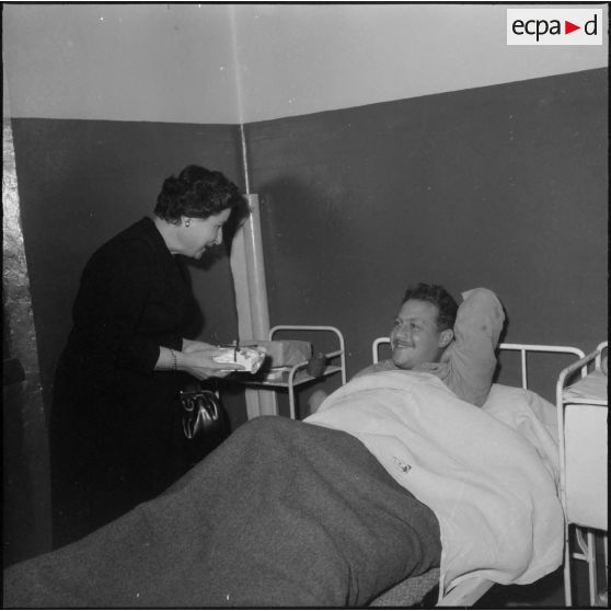 Alger. Infirmerie de garnison. Réveillon de noël 1960. Madame la colonel Santini remet un cadeau à un malade.
