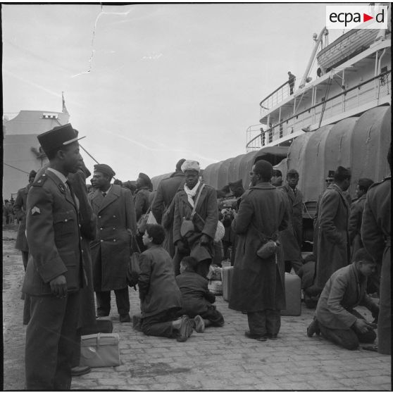 Port d'Alger. Départ des Africains sur le porte-avion Foch. Un dernier coup de brosse sur les chaussures avant d'embarquer.
