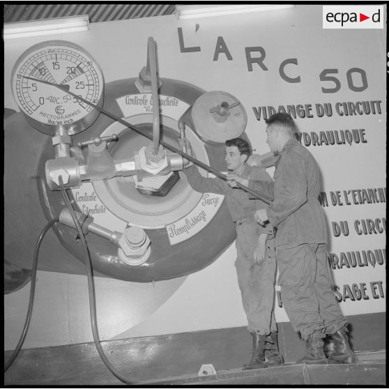 Camp de l'Alma. Centre d'instruction du service du matériel n°3 (CISM 3). Un instructeur montre pendant le cours, à l'aide d'une maquette, le mode de fonctionnement de l'Arc 50.
