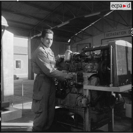 Camp de l'Alma. Centre d'instruction du service du matériel n°3 (CISM 3). Portrait d'un stagiaire devant un moteur.
