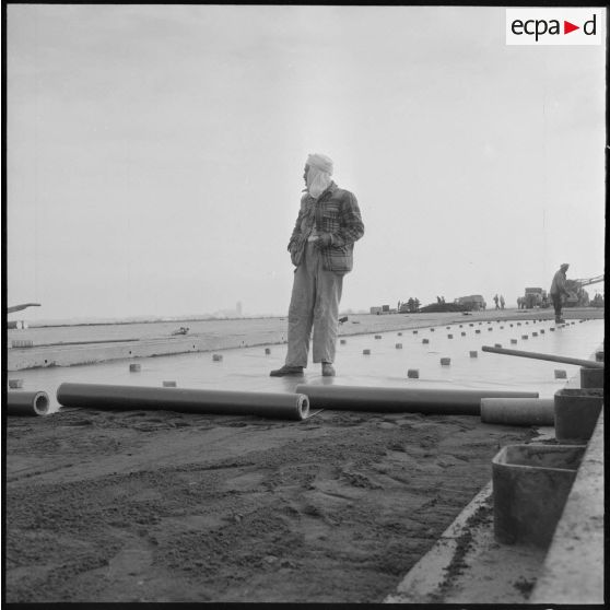 Aérodrome de Maison Blanche. Chantier de la nouvelle piste Est-Ouest en béton précontraint. Les bandes de papier huilé sont déposées sur le sable.