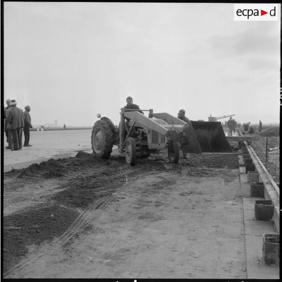 Aérodrome de Maison Blanche. Chantier de la nouvelle piste Est-Ouest en béton précontraint. Dépot du sable sur les couches bitumées.