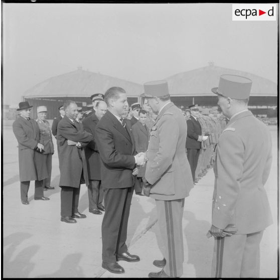 Maison Blanche. Prise d'armes à l'aérodrome pour le départ du général Crépin. Il serre la main à monsieur Verger, chef du cabinet civil et militaire à la direction générale du gouvernement (DGG).