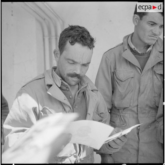 Prisonniers rebelles regardant les photos des prisonniers précédents.