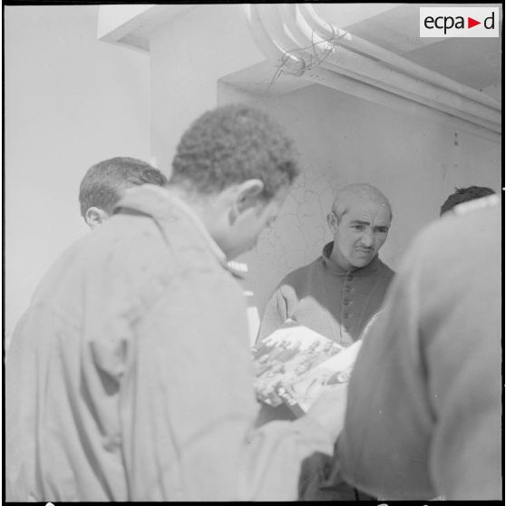 Prisonniers rebelles regardant les photos des prisonniers précédents.