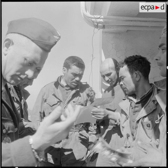 Prisonniers rebelles regardant les photos des prisonniers précédents.