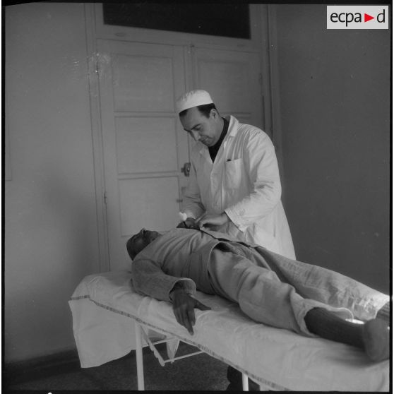 Tlemcen. Hôpital civil. Un médecin ausculte un patient.