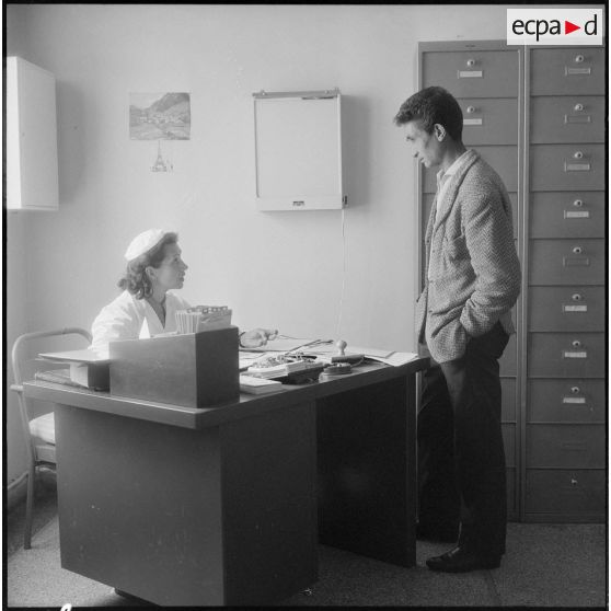Tlemcen. Hôpital civil. Un homme parle à une femme dans un bureau.