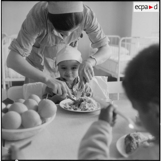 Tlemcen. Hôpital civil. Une femme donne à manger à un enfant.