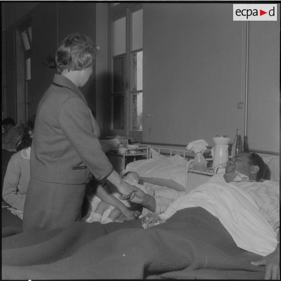 Alger. Hôpital Maillot. Madame Dumonte serrant la main d'un malade que sa jeune femme avec son enfant sont venus voir.