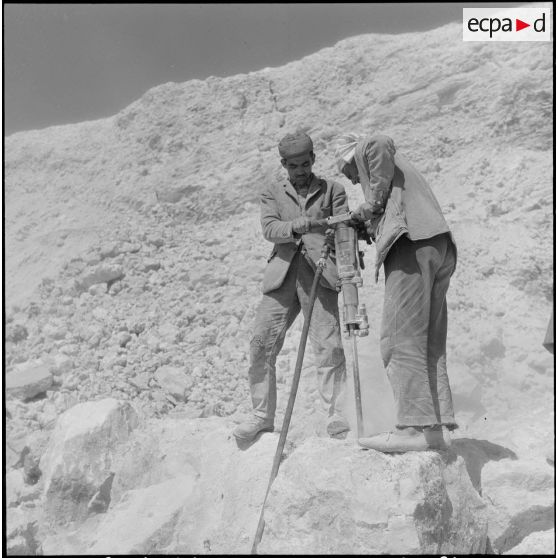 Saint-Lucien. CADO (ciments artificiels d'Oranie). Préparation des trous de charge d'explosifs, pour détruire les gros blocs de ciments.